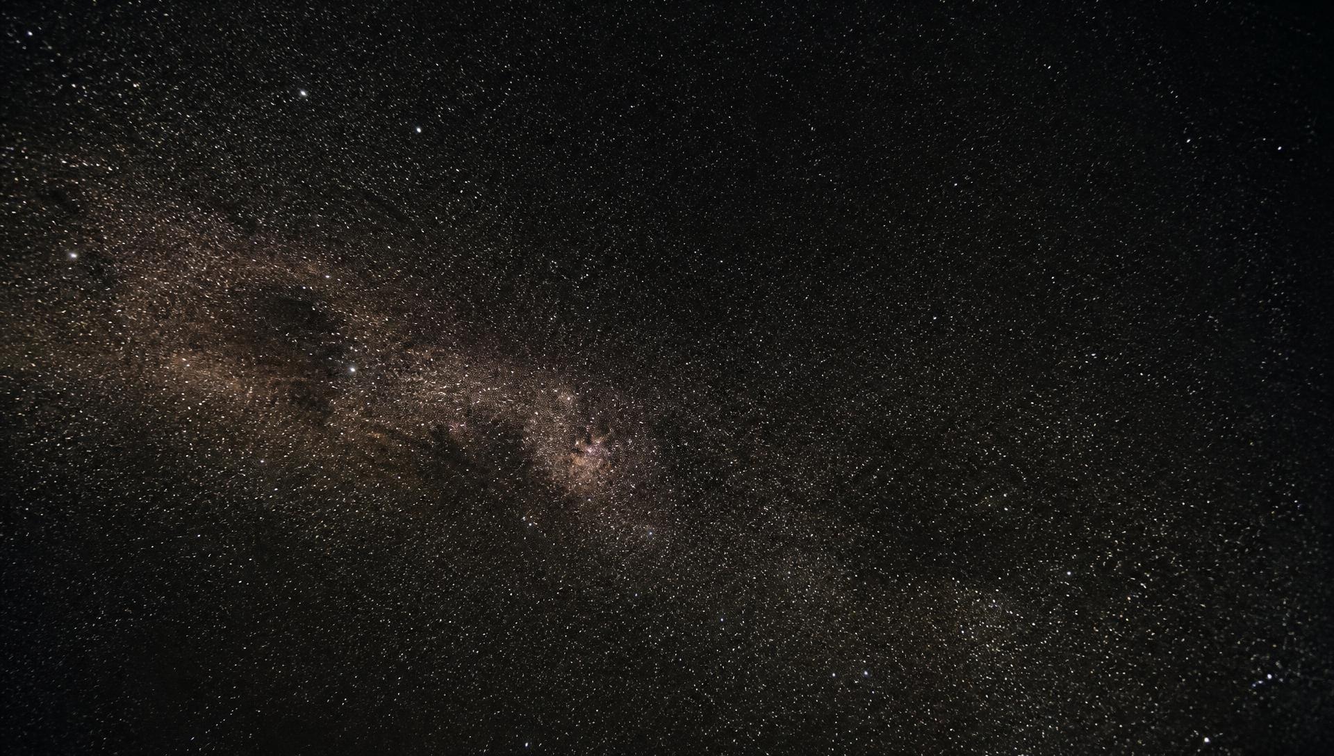 A dense field of stars and the faint band of the Milky Way in a dark sky